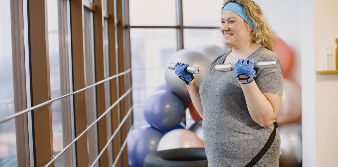 Adult fat woman doing gymnastics at the gym