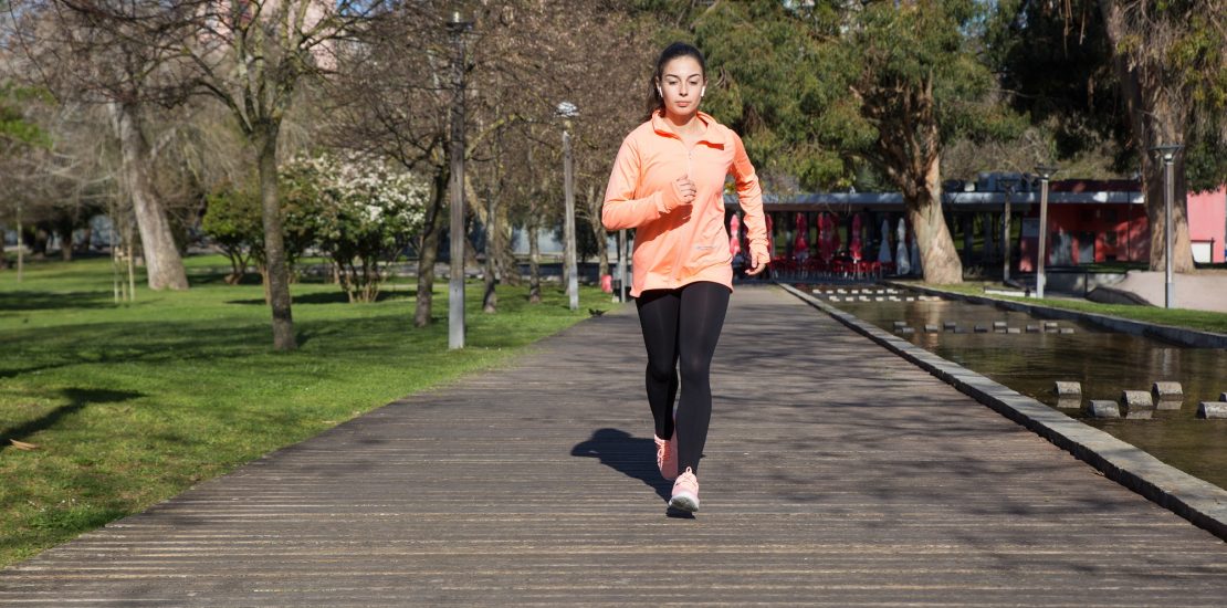 Young pretty woman jogging in city park